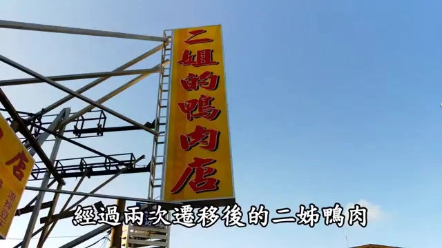 黃底招牌上寫著「二姐的鴨肉店」，掛在鐵架上矗立於藍天下