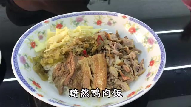 白色花紋瓷盤盛著鴨肉飯，搭配焢肉、酸菜與筍絲，色澤油亮