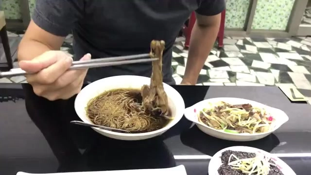 白色湯碗裡盛著當歸鴨腿麵線湯，湯色深褐帶油光，鴨腿完整浮於湯面