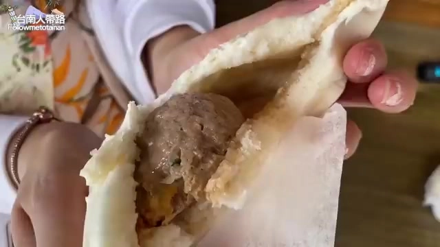 剝開的肉包露出裡面完整的圓形肉丸子，肉餡飽滿，麵皮薄透