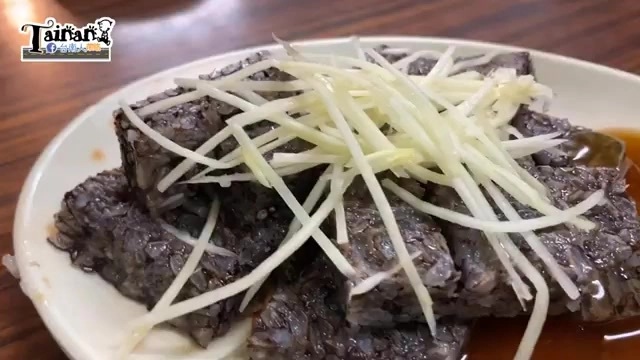 切片的鴨米血鋪上大量薑絲，色澤深黑帶著油亮光澤