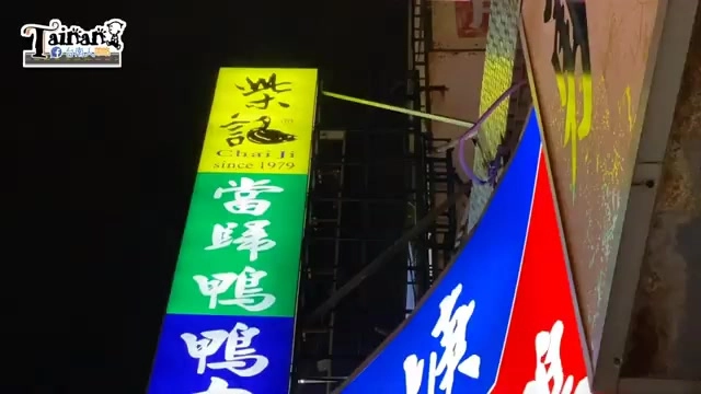 店家招牌在夜晚點亮，藍底白字寫著「柴記」，下方列出「當歸鴨」「鴨肉羹」等品項