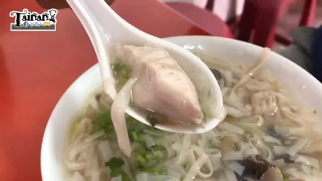 湯匙舀起一塊虱目魚肉，湯裡還有豆簽、蔥花與其他配料
