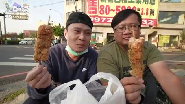 兩人在路邊分別手持一支雞肉串，臉上帶著滿足的笑容，背景可見招牌廣告看板