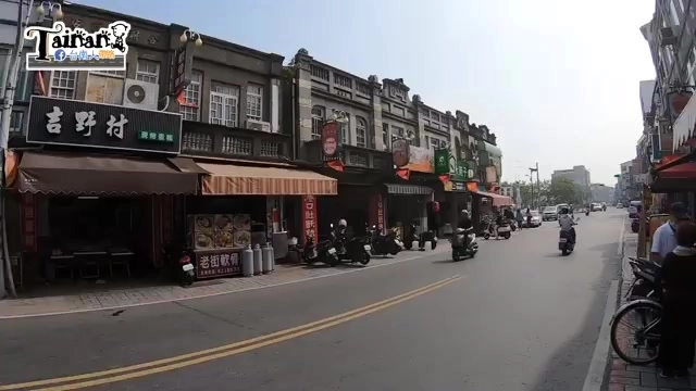 新化老街街景，可見巴洛克式建築立面，左側招牌寫著「吉野村」，店家門口擺放桌椅與招牌