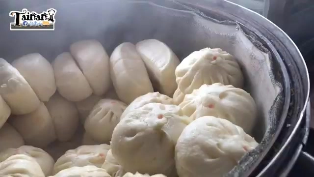蒸籠裡冒著熱氣的多顆包子，表面點著紅色食用印記