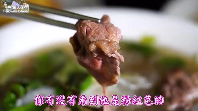 用筷子夾起的粉紅色生牛肉片，正準備放入清澈的湯頭中燙熟