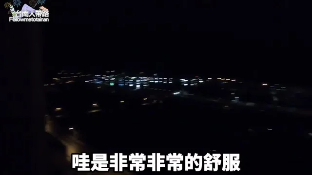 阿波在福容大飯店房內陽台，向鏡頭展示窗外美麗的港灣夜景
