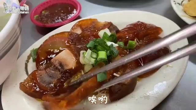 白色圓盤上盛著多片醬色濃郁的滷豬腳,撒上蔥花點綴,一旁附上一碟醬汁