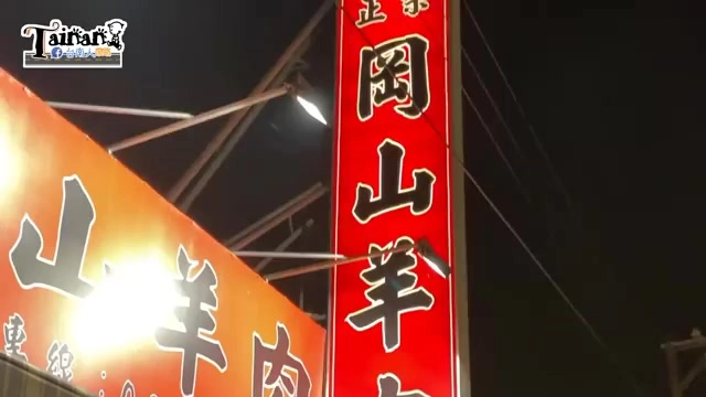 紅底招牌以金字寫著「正岡山羊肉」,夜晚燈光照亮字樣