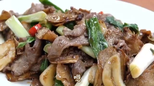 白色瓷盤盛著蔥爆羊肉,肉片帶焦香色澤,搭配蔥段與紅辣椒點綴