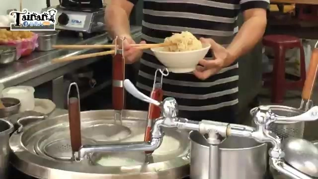 店家在鍋爐前用筷子夾起麵條裝入白色碗中,準備盛裝上桌