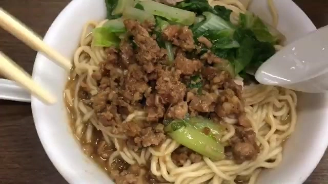 碗中盛著細麵條,鋪滿肉燥與青菜,湯汁均勻裹附在麵條上