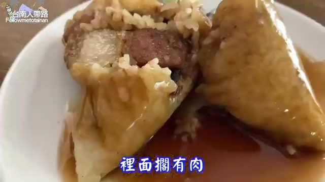 剖開的肉粽露出裡面完整的滷肉塊，糯米淋著醬色滷汁