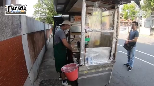 老闆在路邊小貨車攤位前忙碌準備,攤車上掛著透明防雨帆布,一旁站著等候的顧客