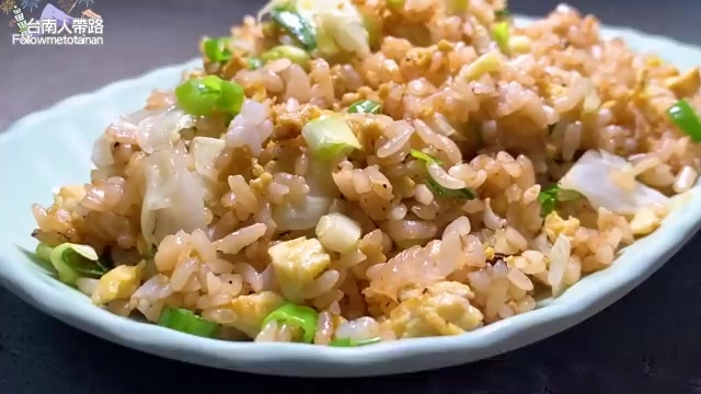 盤中盛著金黃色炒飯，粒粒分明帶著焦香，點綴翠綠蔥花