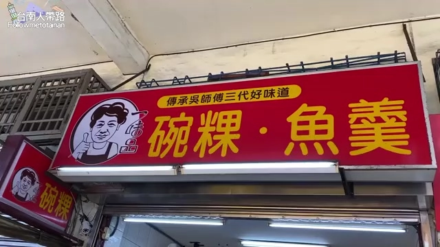 店家招牌高掛在店面上方，紅底黃字寫著「傳承吳師傅三代好味道」與「碗粿·魚羹」