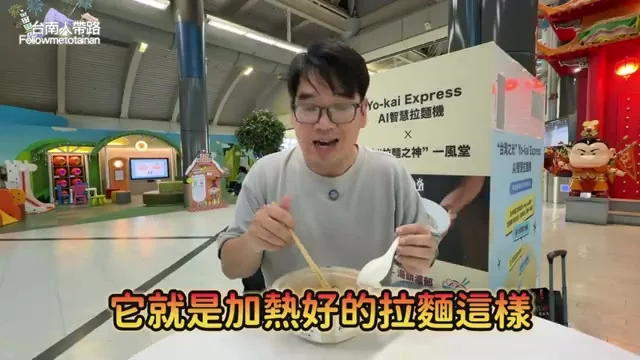 阿波拿著一碗豚骨叉燒拉麵,機場AI拉麵機在後方
