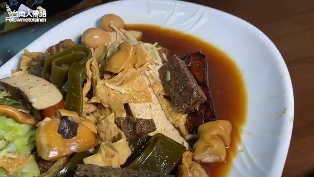 白色盤中盛著多樣滷味拼盤，包含豆皮、豆干、大腸等，淋著醬色滷汁