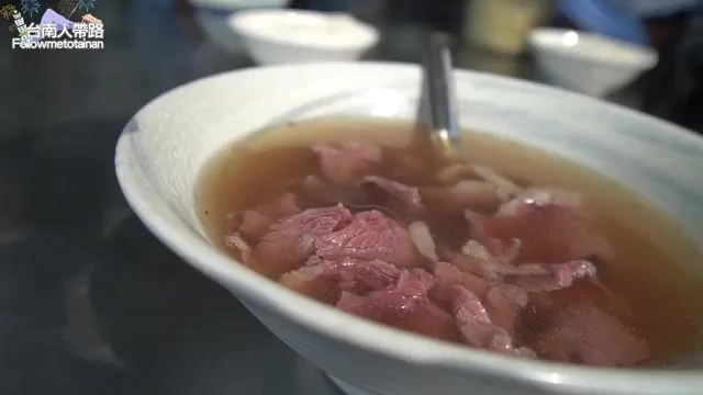 白色瓷碗盛著牛肉湯，湯色偏淡褐色，帶油花的肉片浮於湯面