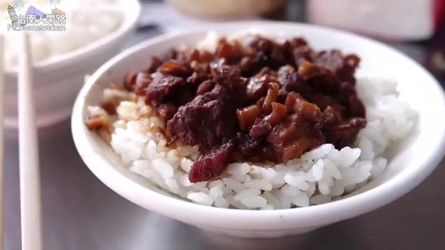 白色瓷碗盛著白飯，鋪上深色滷豬肉燥，色澤油亮