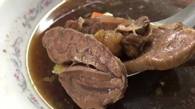 白色瓷碗盛著牛肉塊與紅蘿蔔，湯汁深褐色，肉質紋理清晰