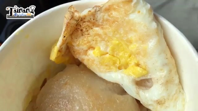 白色碗中盛著肉粿與煎蛋，煎蛋覆蓋在粿塊上，蛋黃流出與醬汁交融