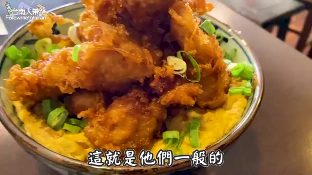 碗中盛滿唐揚雞塊,鋪在滑蛋飯上並撒上蔥花,色澤金黃油亮