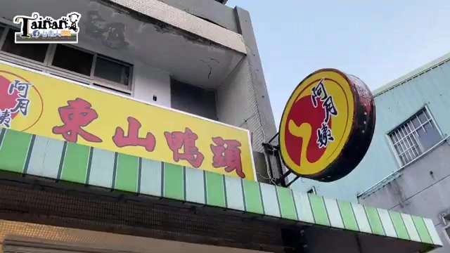 店家招牌高掛在巷弄轉角,黃底紅字寫著「東山鴨頭」,一旁圓形招牌寫著「阿月姨」