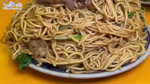 盤中堆疊如小山的炒麵,麵條裹著醬色油亮,夾雜著大片羊肉與青菜