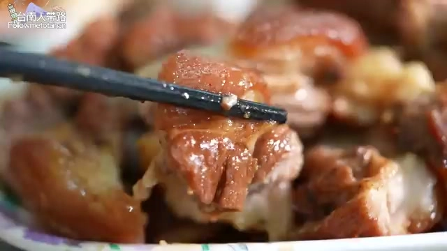 筷子夾起一塊醬色油亮的滷豬腳肉,肉質軟嫩多汁