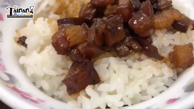 白色花紋瓷碗盛著白飯，鋪滿深色油亮的滷肉丁，色澤誘人