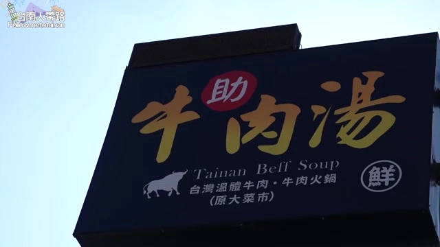 深藍底招牌上以金色字體寫著「助牛肉湯 Tainan Beef Soup」,標示台灣溫體牛肉、牛肉火鍋