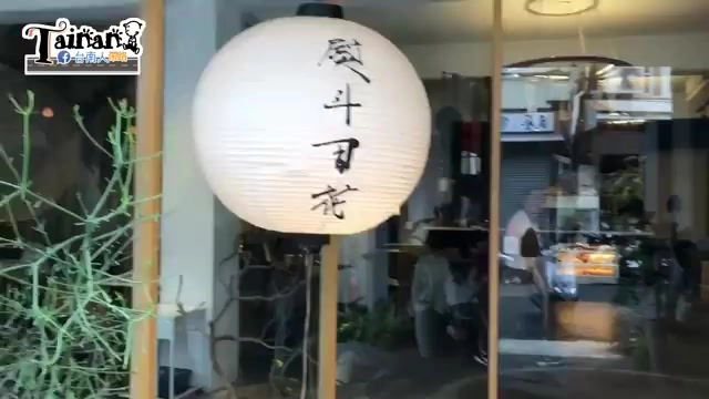 店門口懸掛白色圓形燈籠，上面以毛筆字寫著「熨斗目花」，後方可見玻璃拉門與街景
