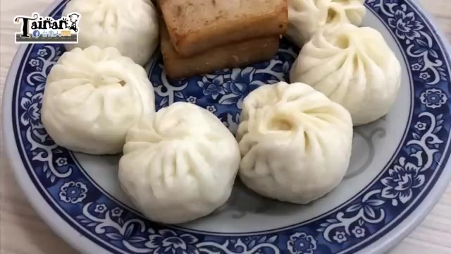 藍白花紋瓷盤盛著白胖的包子與旁邊的滷味色澤點心