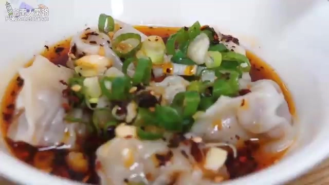 白色碗中盛著紅油抄手,淋上油亮紅油並撒上翠綠蔥花,賣相誘人