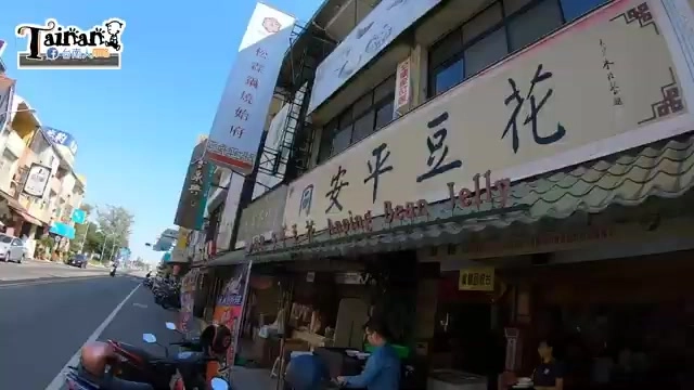 店面外觀,紅底招牌寫著「同安平豆花 Anping Bean Jelly」,木造牆面貼滿新聞報導剪報,門口停放機車