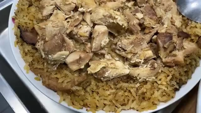 白色圓盤盛著麻油雞飯,油亮的米飯上鋪滿雞肉塊,色澤金黃