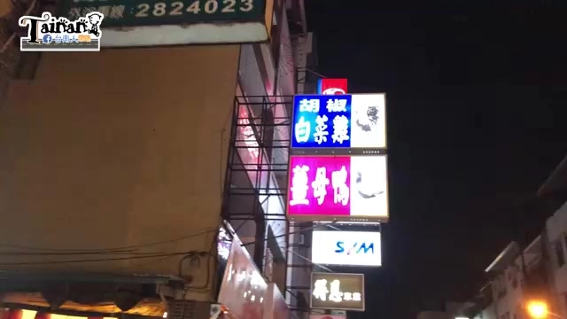 夜晚拍攝的店家招牌，藍底白字寫著「胡椒白菜雞」，紫底白字寫著「薑母鴨」，燈光醒目