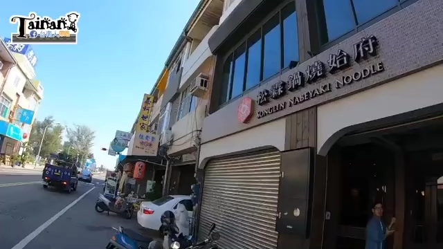 店面外觀，黑底招牌寫著「松霖鍋燒始府 SONGLIN NABEYAKI NOODLE」，鐵捲門半開，一旁停放機車