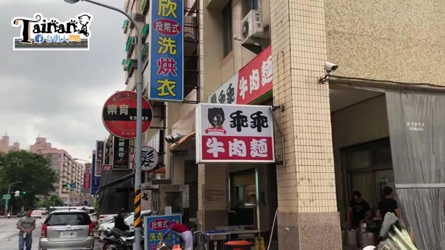 店面外觀，紅底白字招牌寫著「乖乖牛肉麵」，上方懸掛黑底標誌，一旁還有洗衣店招牌