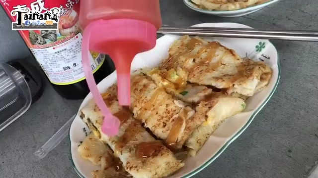特寫切開的蛋餅,粉紅色醬料瓶正淋上醬汁,餅皮呈現金黃色澤與蔥花點綴