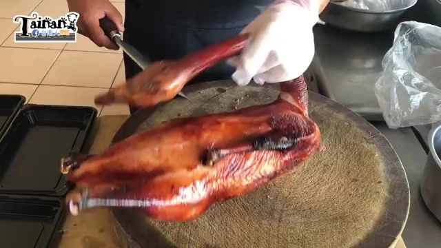 整隻燒鵝掛在鉤架上,表皮呈現深紅焦糖色澤,油亮誘人