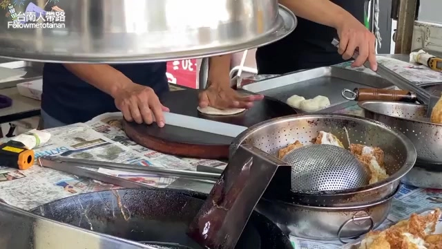 老闆手持鐵盤在爐台前擀麵皮,一旁的油鍋正炸著蔥油餅