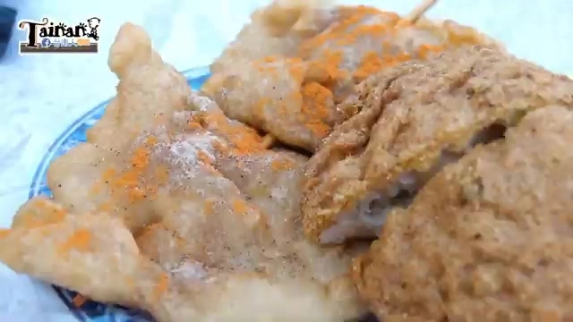 剖開的炸物特寫,撒著橘紅色辣粉與胡椒,外皮呈現金黃色澤