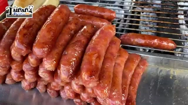 烤架上排列著多條紅亮的香腸,油光發亮,正在燒烤加熱