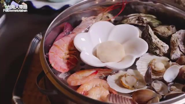 不鏽鋼蒸盤上盛滿新鮮蝦子、牡蠣、扇貝與貝類，中央擺著白色花型小碟盛裝干貝