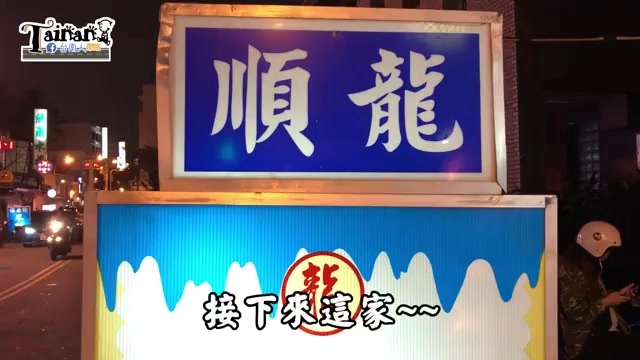 路邊攤位招牌，藍底白字寫著「順龍」，下方黃藍相間的招牌立在夜市街頭