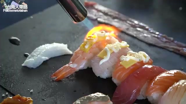 師傅手持噴槍現場炙燒握壽司，鮭魚、鮪魚等生魚片整齊排列