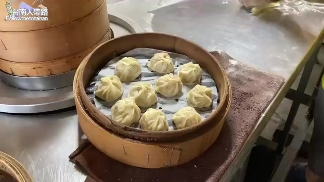 竹製蒸籠中整齊排列著九顆小籠包，表面褶皺清晰可見，蒸氣氤氳